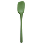 The Flex-Core Spoonula is a green kitchen tool with a long handle and a slightly curved, rectangular head, designed ergonomically for cooking and baking.