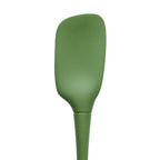 The tovolo Flex-Core Silicone Spoonula, in green, features a wide, slightly curved blade and a tapered handle, displayed against a white background.