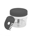 The Twist and Chop Mini Mincer, a compact clear plastic garlic chopper with a black lid and stainless steel blades, sits beside a black plastic comb-shaped tool embossed with “Tovolo”.