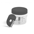 The Twist and Chop Mini Mincer, a compact clear plastic garlic chopper with a black lid and stainless steel blades, sits beside a black plastic comb-shaped tool embossed with “Tovolo”.