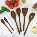Five Beechwood Utensils, including an angled turner, are arranged on a marble countertop with fresh tomatoes, green peppers, a white towel, a small bowl of oil, and grains—ideal for non-stick cookware.