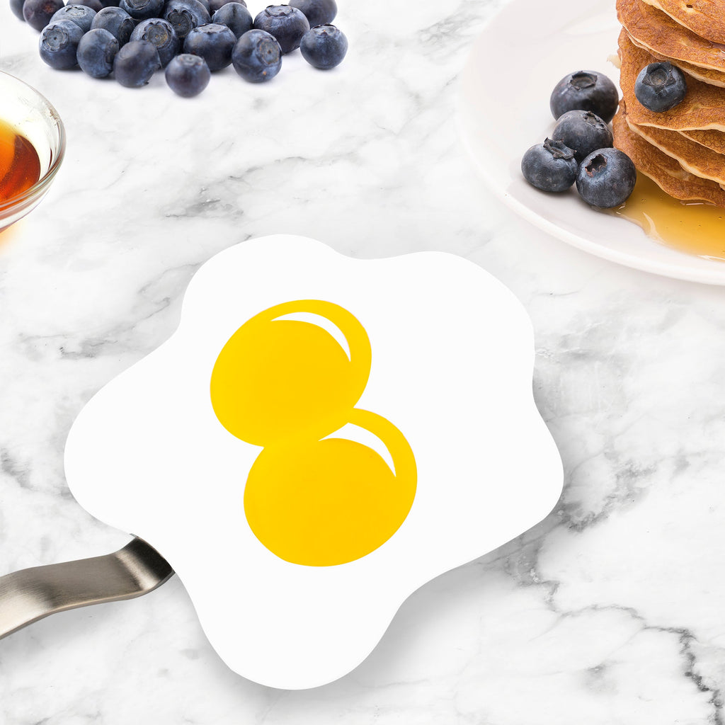 A cartoon-style image of two egg yolks on the Spatulart Flex Turner, set on a marble countertop with blueberries, pancakes, and syrup—ideal for anyone who enjoys cooking on nonstick skillets.