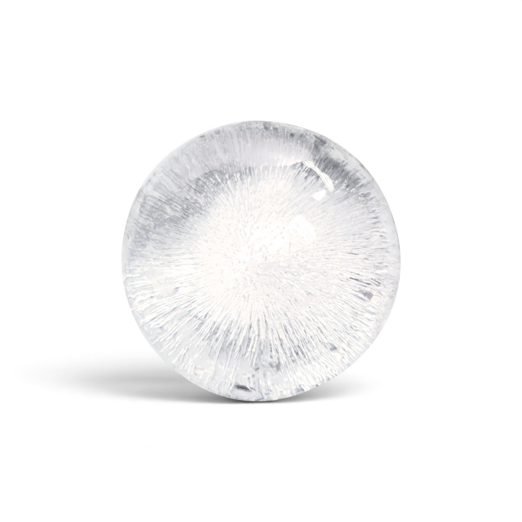 A clear, round ice sphere with intricate cracks and air bubbles made using tovolo Sphere Ice Molds (Set of 2), set against a white background.