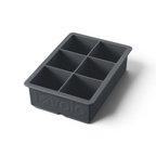 The tovolo King Cube Silicone Ice Mold is a black tray with six large square compartments, ideal for crafting big ice cubes. The word "tovolo" is embossed on the front of this craft ice mold.