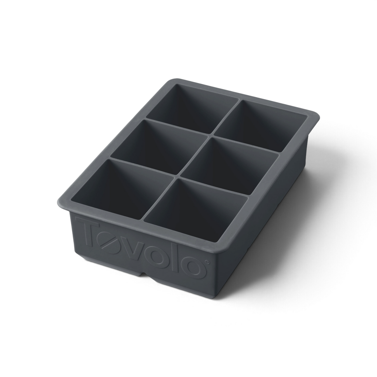 The tovolo King Cube Silicone Ice Mold is a black tray with six large square compartments, ideal for crafting big ice cubes. The word "tovolo" is embossed on the front of this craft ice mold.
