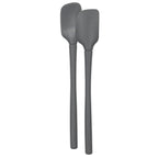 The Flex-Core Mini Spat + Spoonula, two gray heat-resistant silicone kitchen utensils, stand upright side by side against a white background.