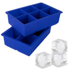 The tovolo King Cube Silicone Ice Molds (Set of 2) are stacked, each featuring six large compartments, with three clear craft ice cubes in front—ideal for chilling drinks without dilution.