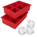 Two red tovolo King Cube Silicone Ice Molds (Set of 2), each with six large square compartments, are stacked. In front, three large clear craft ice cubes are displayed.
