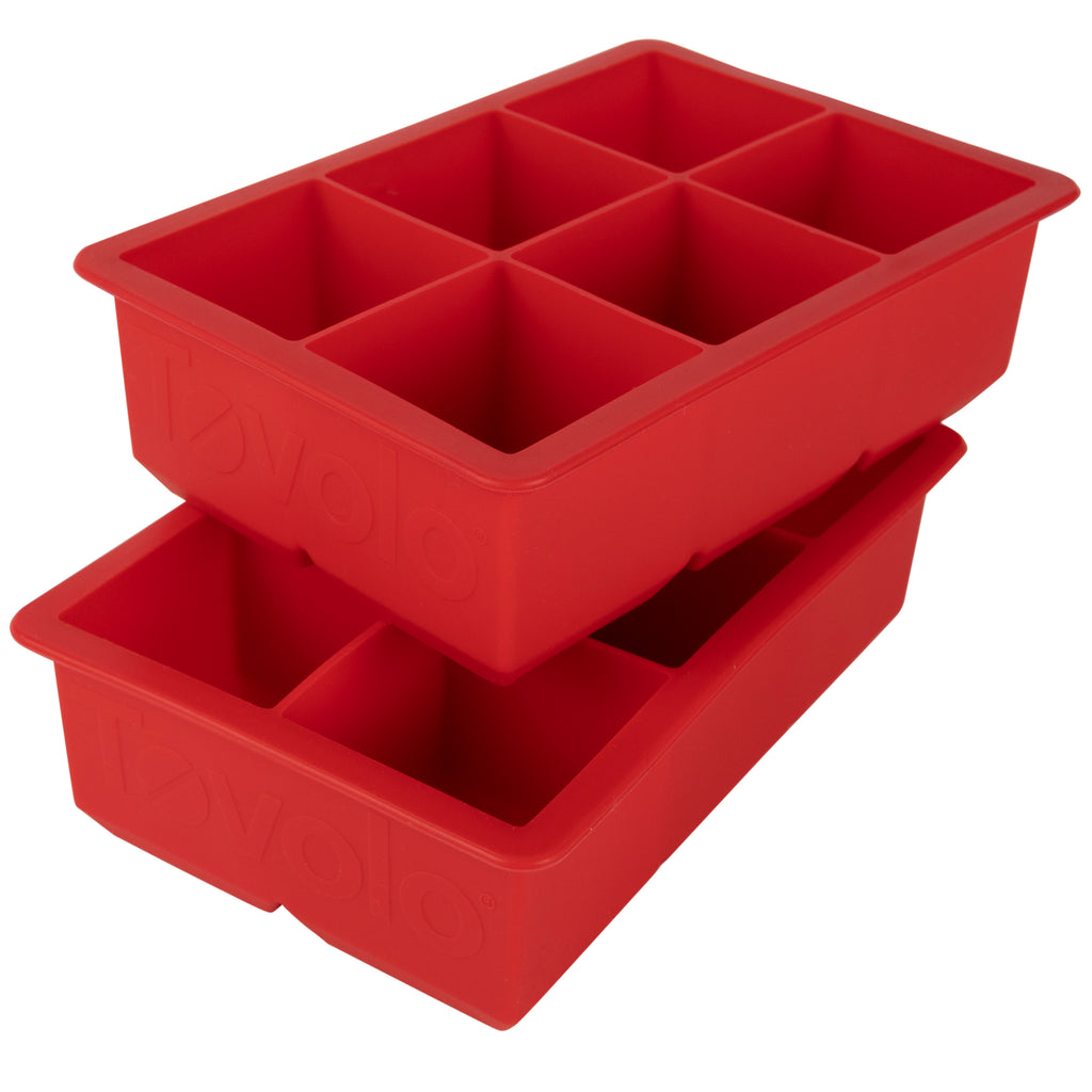The tovolo King Cube Silicone Ice Molds (Set of 2) are red trays, each featuring six large square compartments, stacked slightly askew.