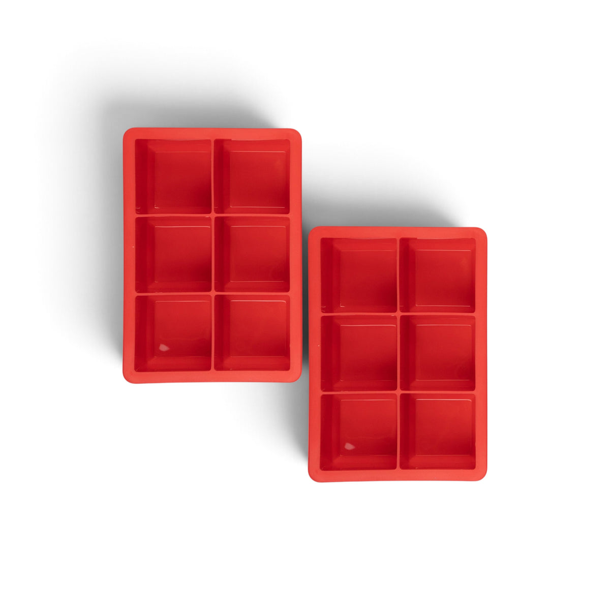 The tovolo King Cube Silicone Ice Molds (Set of 2) feature six large square compartments each, perfect for making craft ice cubes. The red trays are set against a white background, ideal for creating large ice cubes at home.