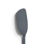 The Flipping Flex Turner is a gray silicone spatula with a slightly curved, smooth blade and a sturdy steel handle, perfect for nonstick cookware, shown isolated on a white background.