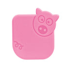 The Pan Scrapers are pink, square-shaped tools with rounded edges, featuring a pig face in the top right and a curly tail at the lower left—ideal for cleaning non-stick bakeware and cast iron skillets. Shown on a white background.