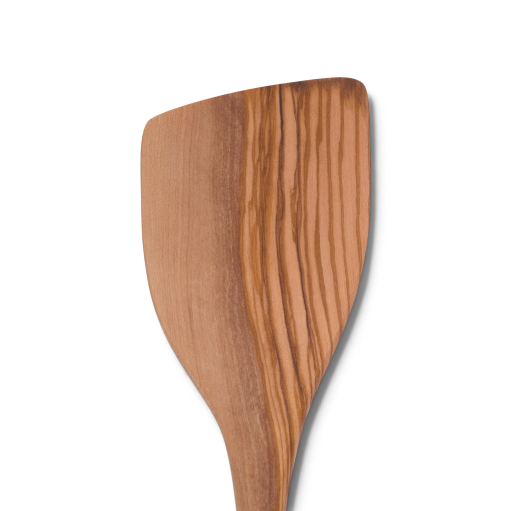 A close-up of Olivewood Utensils featuring a pancake turner with a smooth finish and unique wood grain patterns, nonstick safe and beautifully displayed against a white background.