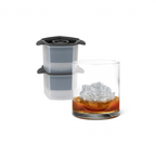A glass of whiskey features a large, detailed rose-shaped ice cube. In the background, Tovolo Rose Ice Molds (Set of 2) with dark lids are stacked, showcasing the perfect way to create stunning rose ice cubes.
