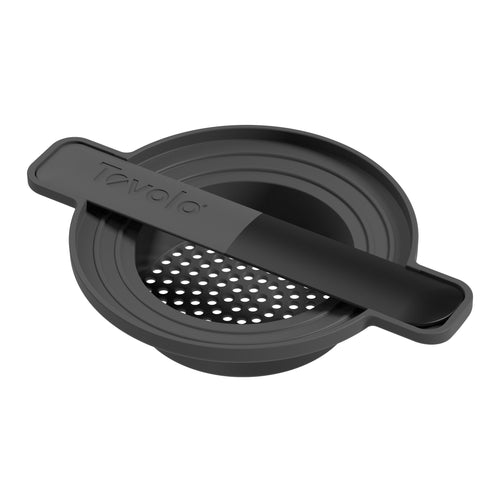 The Can Do Strainer is a black silicone drink strainer with a flat handle and round base, designed to fit over a glass and filter ice or fruit through small holes when pouring drinks.