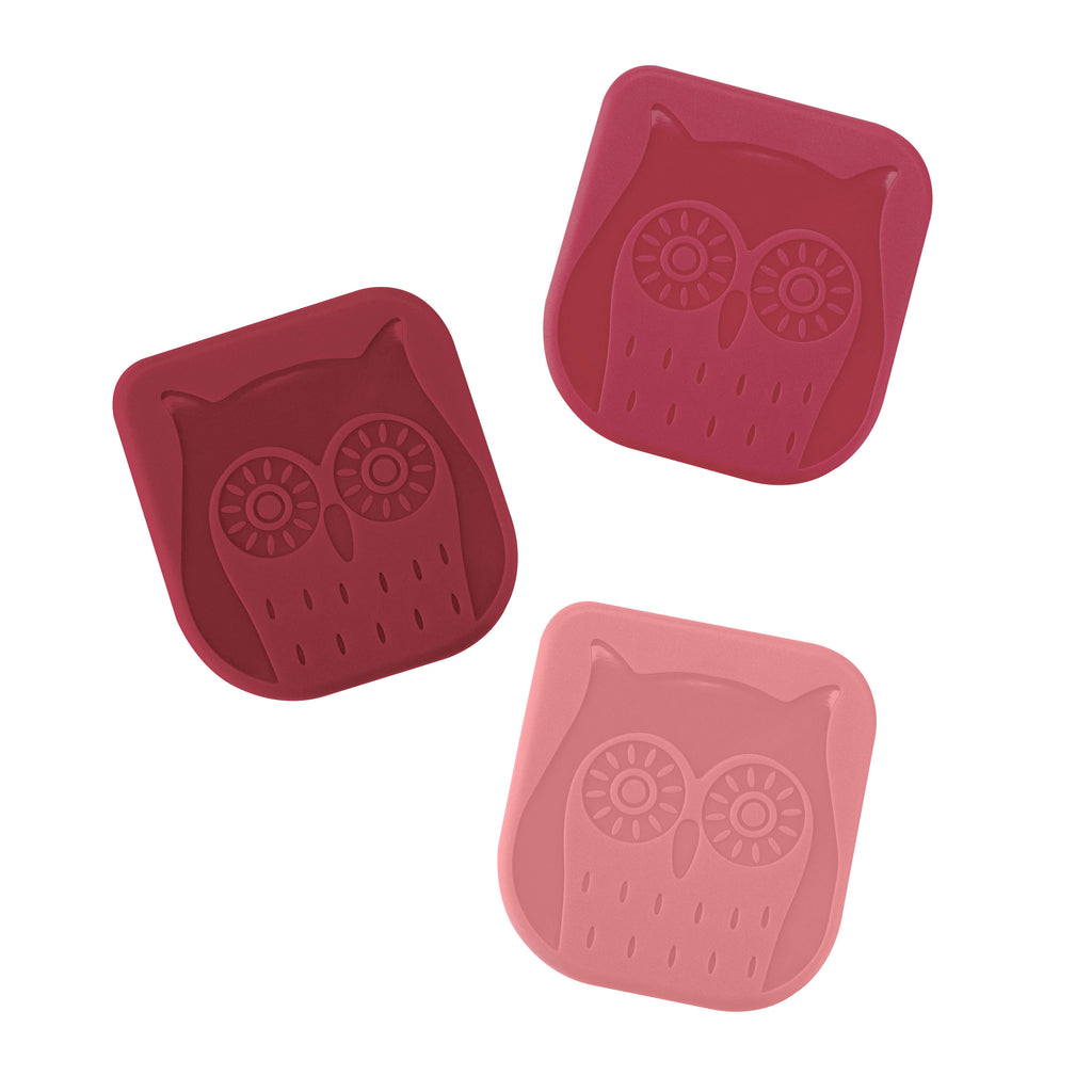 Three red and pink square silicone pan scrapers, each with an embossed owl face, are designed for cleaning non-stick bakeware or cast iron skillets.