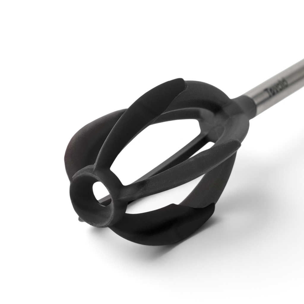 A close-up of the Better Batter Tool, a black, flower-shaped silicone kitchen whisk with a stainless steel handle, set against a white background.