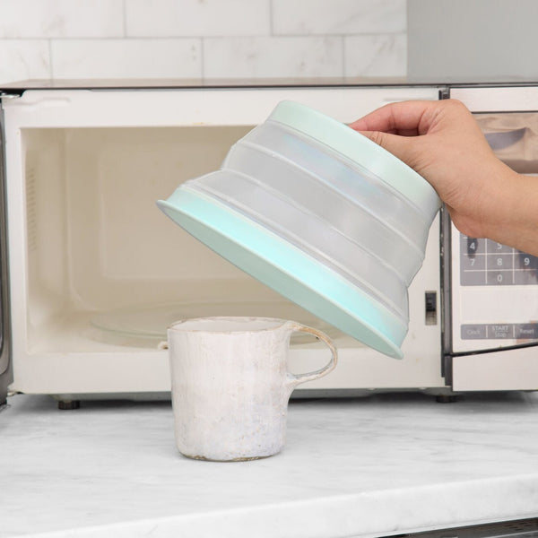 Person using a silicone kitchen tool to clean inside a microwave.